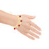 A hand adorned with a striking Red Evil Eyes Tiny Elephant Charm bracelet, featuring red and black circular beads on a 14k gold-filled adjustable band, elegantly displayed on a white background.